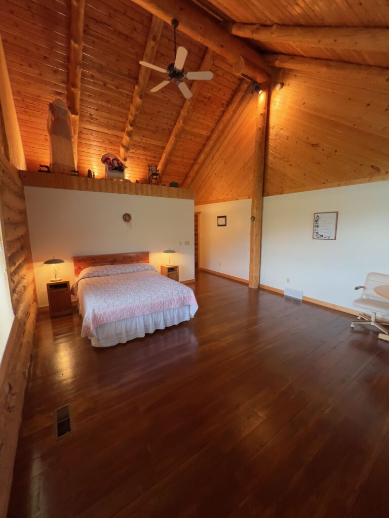King bedroom with warm lighting and log beams