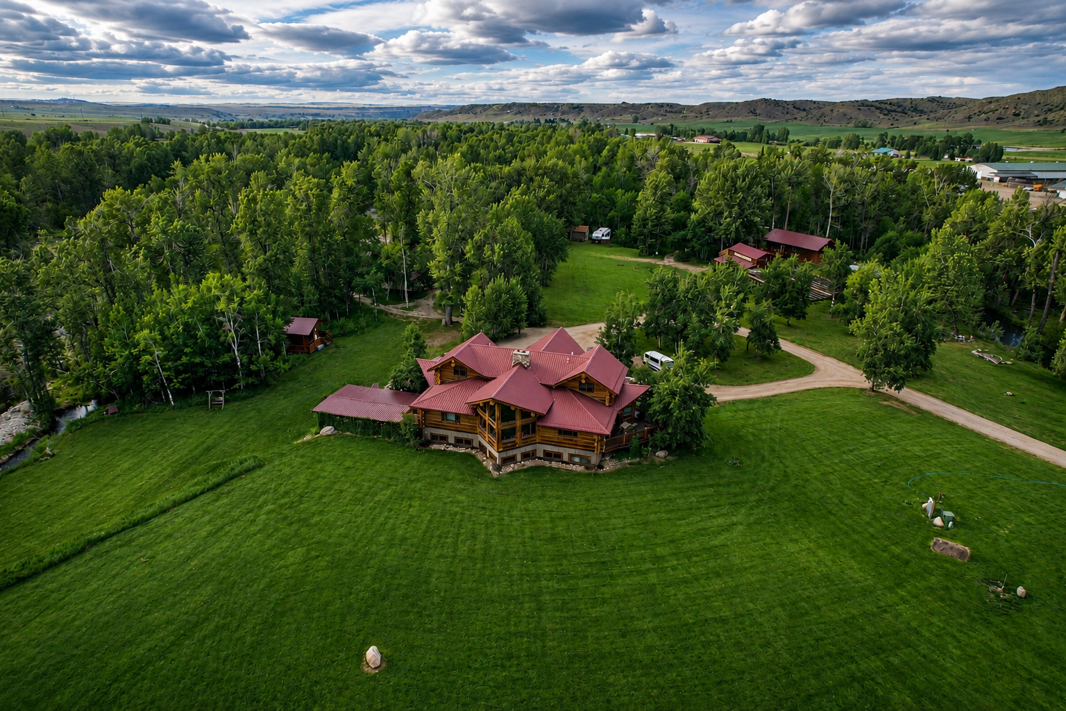 Aerial view of The Flagship Lodge main house and outbuildings surrounded by cottonwoods and open meadow
