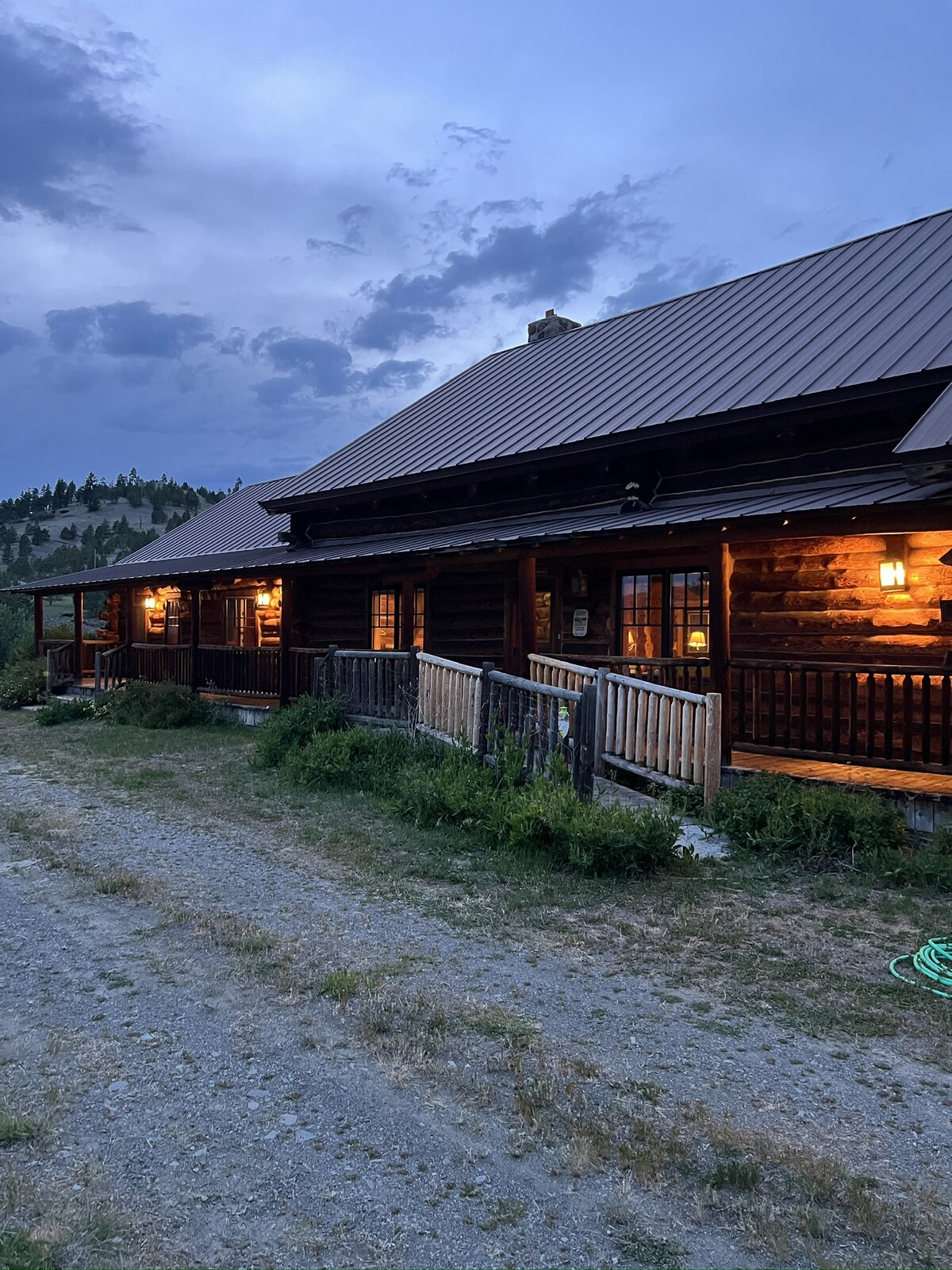 Spring Creek Lodge log exterior at dusk with warm-lit windows and a wraparound porch