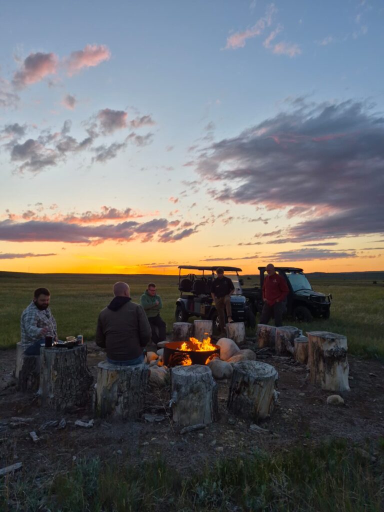 Guests around a sunset campfire on the range